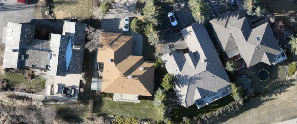 Drone image of four neighbouring houses, with trees covering parts of the roofs